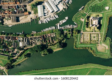 Aerial top view of the Muiderslot castle in Muiden near Amsterdam and its lush gardens at the IJsselmeer with surrounding water entrenchment and port area of the village in the foregro