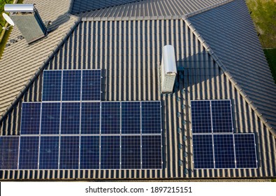 Aerial Top View Of New Modern Residential House Cottage With Blue Shiny Solar Photo Panels System On Roof. Renewable Ecological Green Energy Production Concept.