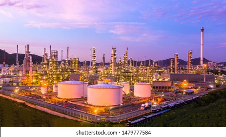 Aerial top view oil and gas tank with oil refinery background at night, Business petrochemical industrial, Refinery factory oil storage tank and pipeline,  Ecosystem and healthy environment concepts.