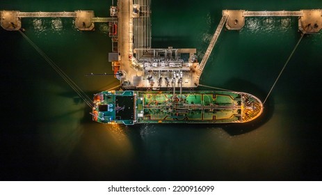 Aerial Top View Oil Tanker Ship At Terminal Industrial Port At Night For Transfer Crude Oil To Oil Refinery, Business Import Export Oil And Gas Petrochemical.