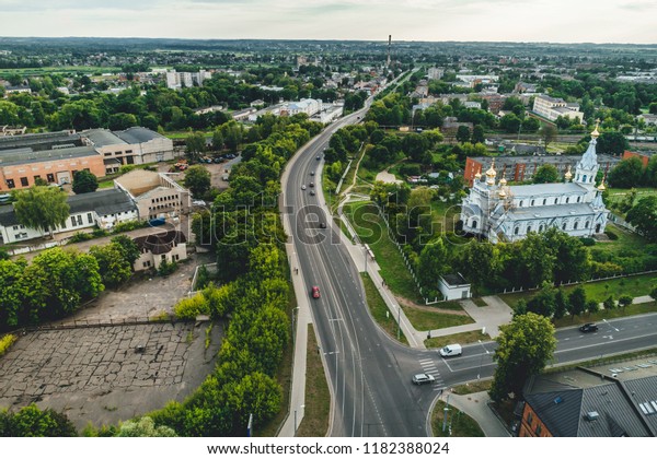 Aerial top view on road in city, junction\
and city traffic, cars on road, house rooftops\
