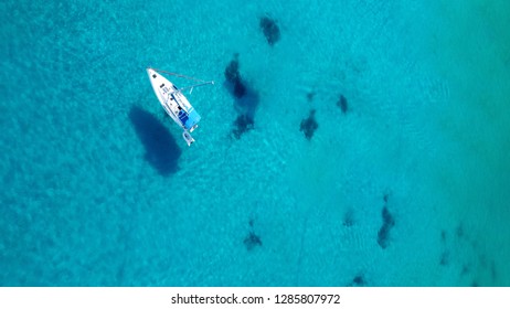 Aerial top view photo of yacht cruising in turquoise clear sea of Ionian island