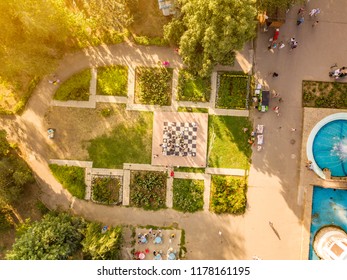 Aerial Top View Of Public City Summer Park With Crowd Of People Walking By The Fountains