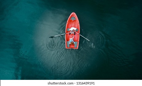 Aerial top view. Red boat on the lake, top view. Two young peopl