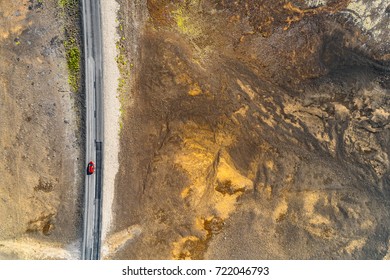 Aerial Top View Of Red Car Driving On Iceland Road Trip Travel Adventure. Drone Helicopter Shot From Above Of Volcanic Desert Landscape. Highway Crossing Through Volcano Mountains, Nature Background.