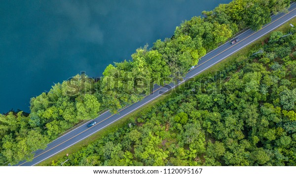 Aerial\
top view road track with car and river, around the tree and forest,\
Aerial view of the road through river and\
forest.