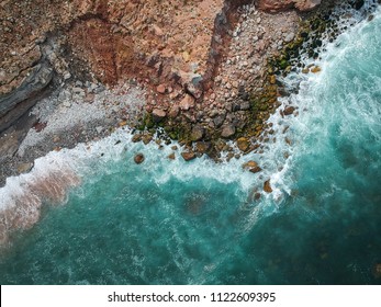 Aerial top view of sea waves hitting rocks on the beach with turquoise sea water. Amazing rock cliff seascape in the Portuguese coastline. Drone shot. - Powered by Shutterstock