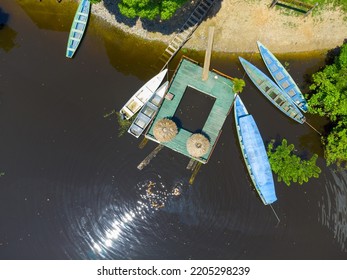 Aerial Top View Of A Small Wooden Pier And Some Conoes In The Amazon River In The Middle Of The Forest In Brazil