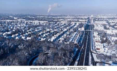 Aerial top view of snow covered Autobahn highway in the south of Munich surrounded by forest in winter