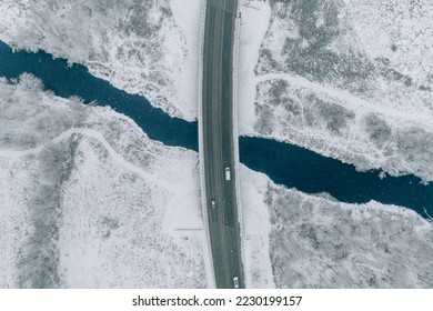 Aerial top view of snow winter road with cars over blue river - Powered by Shutterstock
