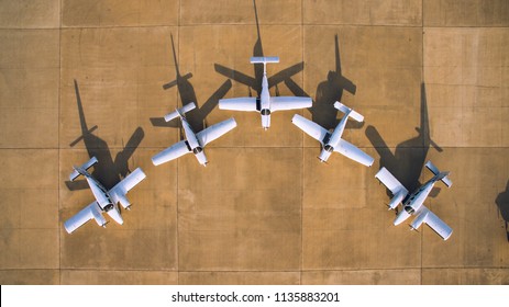 Aerial top view of a symmetry parked light aircrafts at a small countryside airfiled. Cessna and Piper