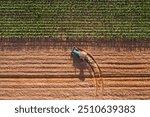 Aerial top view tractor plowing a field , preparing the land for a wheat planting operation.