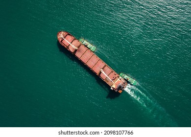 Aerial Top View Tugboat Pulling Red Oil Ship To Shipyard Dry Dock Repairing And Maintenance In Green Sea 