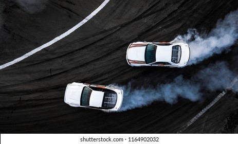 Aerial top view two car drift battle on asphalt race track, Automobile and automotive car view from above, Professional car drifting, Race drift car with white smoke from burning tires on speed track.