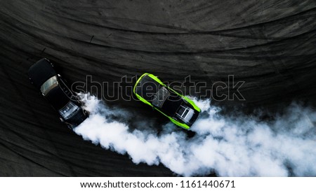 Aerial top view two car drifting battle on asphalt street road race track, Two race car drag view from above, Car turbo drifting, Race drift car with white smoke from burning tire on speed track.