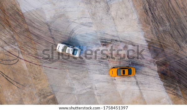 Aerial top view two car drifting battle on asphalt
street road race track, Two race car drag view from above, Car
turbo drifting, Race drift car with white smoke from burning tire
on speed track.