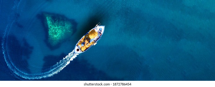 Aerial top view ultra wide photo of beautiful traditional fishing boat from famous small picturesque village of Parga with turquoise crystal clear sea, Ionian, Greece