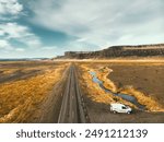 Aerial top view white camper van vehicle parked on side of ring road in Iceland highlands. Drive road trip Icelandic southern ring road in scenic mountains and wild landscape. Iceland travel concept