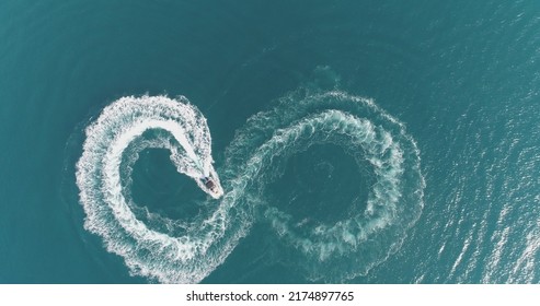 Aerial top view of a white pleasure boat on a summer day. Powerboat turn loop eight on the sea making metaverse infinity future concept. 