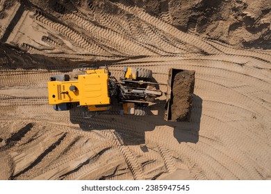 Aerial top view yellow industrial excavator working on sand quarry. Concept Open pit mine industry.