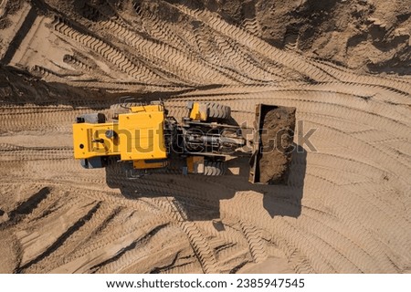 Aerial top view yellow industrial excavator working on sand quarry. Concept Open pit mine industry.
