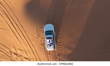 AERIAL. Top view of young couple relaxing on the car's roof at the desert. - Powered by Shutterstock