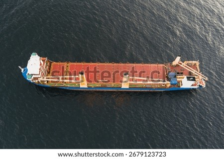 Aerial top-down drone view of a large general cargo ship with cranes sailing on the dark Baltic Sea.