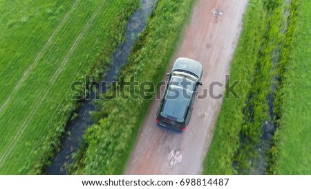 Aerial top-down photo of offroad SUV sport utility vehicle driving fast over unpaved gravel road in between two straight canals off-road truck driving fast in straight direction
