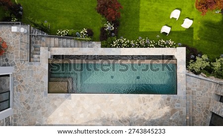 Aerial top-down view of a luxury rectangular swimming pool and stone patio