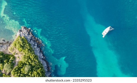 Aerial top-down view of a sailboat anchored in a turquoise bay on the Greek Ionian Sea. Aerial drone ultra wide photo of sail boat anchored in deep blue Mediterranean Sea - Powered by Shutterstock