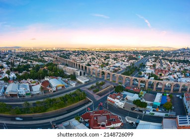 Aerial Tour Over The Famous Aqueduct Of Querétaro In The Center Of The City Surrounded By Constructions With A Beautiful Sunrise In The Background