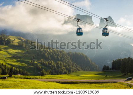 Aerial Tram Cable Car going up, during sunset, with beautiful high mountains in the background in Alpe di Siusi, Dolomites, Italy