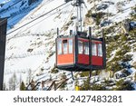 Aerial tramway passenger cabin approaching the lower station in the Alps on a sunny winter day