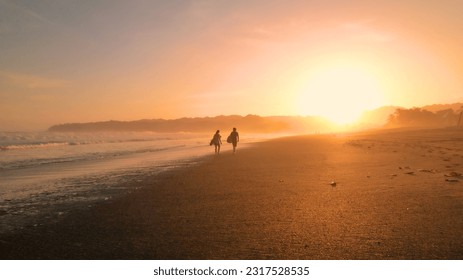 AERIAL: Two friends share their impressions of surfing while walking on beach. Incredible surfing location at amazing golden glowing Playa Venao beach with rolling waves of Pacific Ocean in Panama. - Powered by Shutterstock