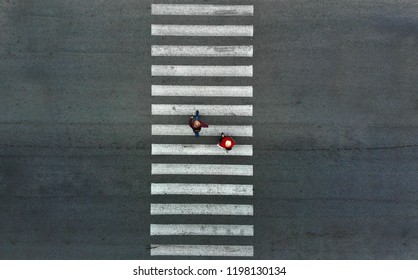 Aerial. Two Pedestrians Walk On A Pedestrian Crossing.