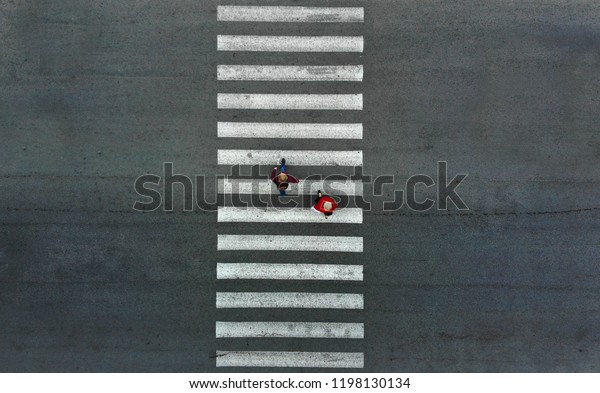 Aerial.\
Two pedestrians walk on a pedestrian\
crossing.