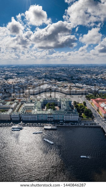 Aerial vertical panorama of Saint Petersburg,\
Russia, Hermitage museum, Winter Palace, Palace Square, embankment,\
boats on the Neva river, green roofs, Alexander column, Arch of\
General Staff