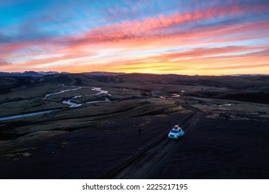 Aerial view of 4wd car parked on dirt road among moss lava field in the sunset on Icelandic highlands in summer of Iceland
