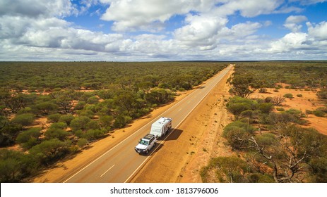 Aerial View Of 4WD Vehicle And Modern Caravan Travelling A Highway In The Outback Of Australia