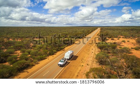Aerial View of 4WD vehicle and modern caravan travelling a highway in the outback of Australia