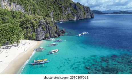 Vista Aéreas de la Playa de 7 Comandos en El Nido, Palawan con aguas turquesas, embarcaciones amarradas a lo largo de la costa. Exuberantes acantilados, palmeras. Paraíso tropical, serena escena costera.