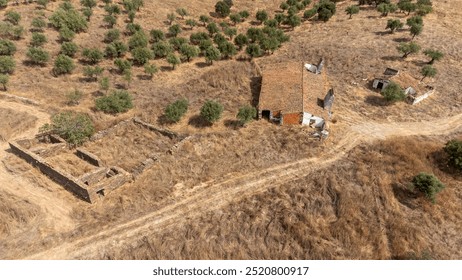 Aerial view of an abandoned rural hilltop estate in the Alentejo, Portugal. Crumbling stone structures surrounded by dry, golden fields. Peaceful, yet weathered. - Powered by Shutterstock