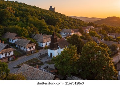 Aerial view about a tiny village named Hollókő with spectacular summer sunset over Cserhát mountains. Famous tourist destination, Unesco world heritage site. - Shutterstock ID 2169512863