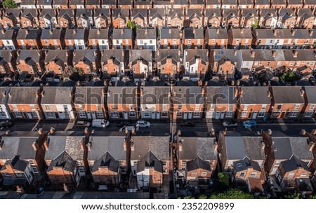 An aerial view above the drab rooftops of run down back to back terraced houses on a large residential estate in the North of England