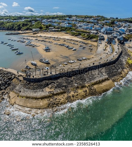 An aerial view above the harbour breakwater towards the town at New Quay, Wales in summertime