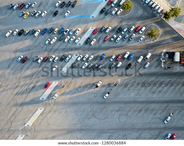 Aerial view above an outdoor car park with\
colorful cars parked at an angle at sunset with long shadows and\
tire marks on the\
asphalt