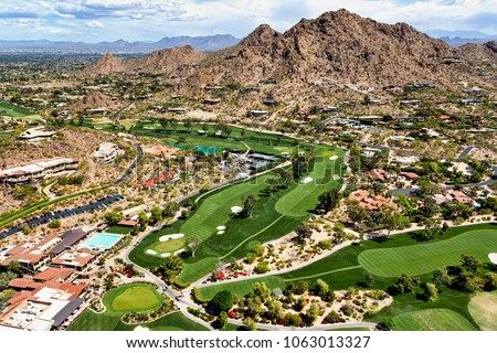 Aerial view from above a scenic golf course in Paradise Valley, Arizona looking to the northeast at Mummy Mountain and the McDowell Mountains in the distance