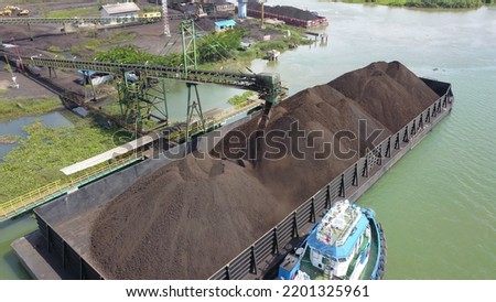 Aerial view of the activity loading coal into barges in a shipyard