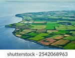 Aerial view of agricultural landscape of Stevns Klint coastline with vibrant green fields and waters of Baltic sea in Denmark