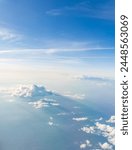 Aerial view from airplane window above green ground. View from the airplane window with beautiful clouds at sunrise. Earth and sky as seen through window of an airplane.